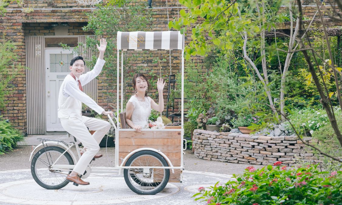 ガーデン入場で自転車にのって手をふる新郎新婦