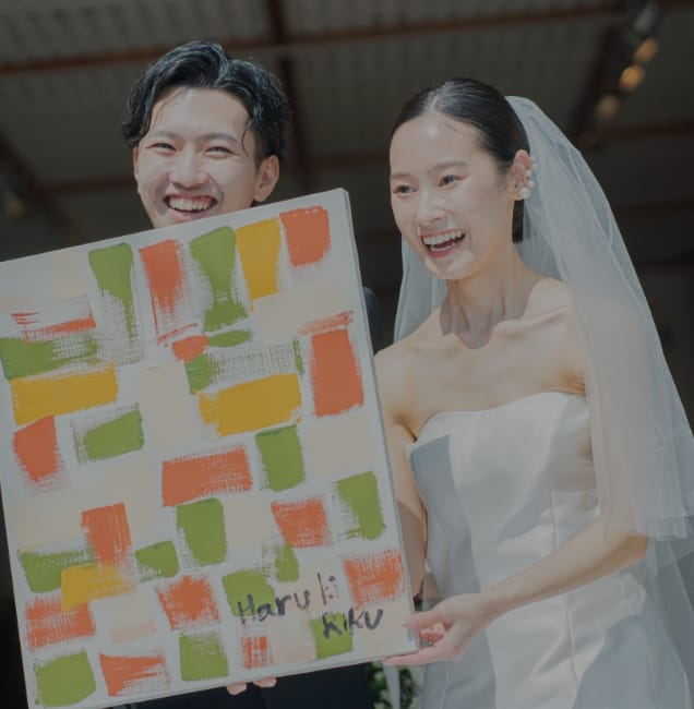絵の具の塗られたキャンパスを持つ笑顔の新郎新婦