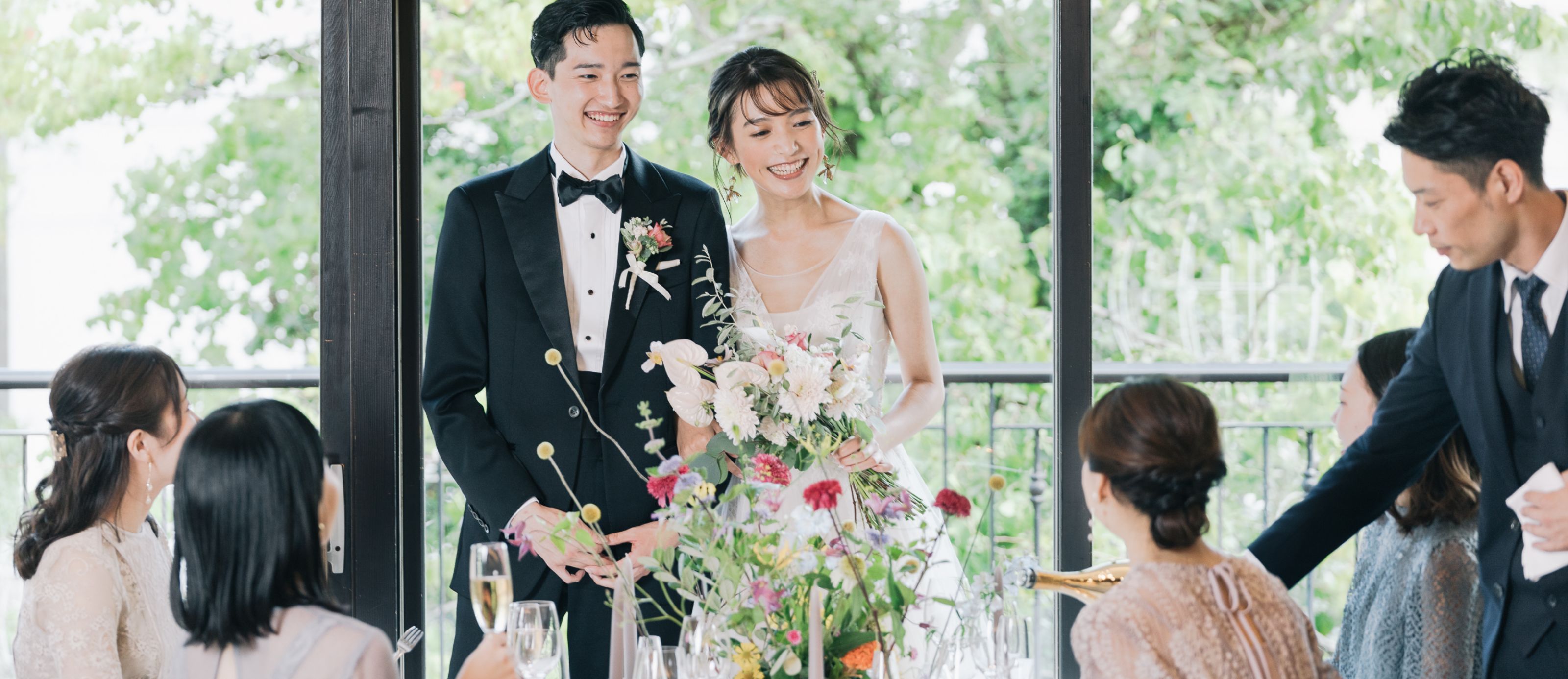 窓際でゲストと話をする新郎新婦